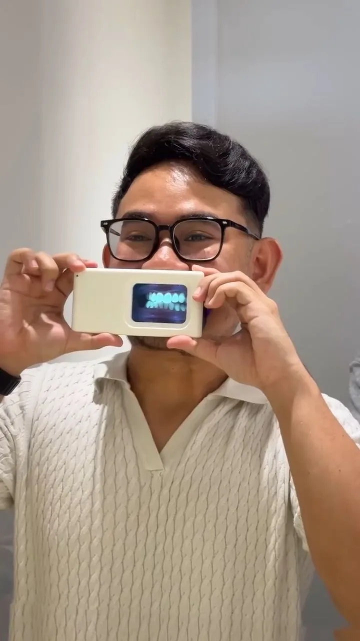 Person holding a plaque-light viewer displaying teeth, image 25